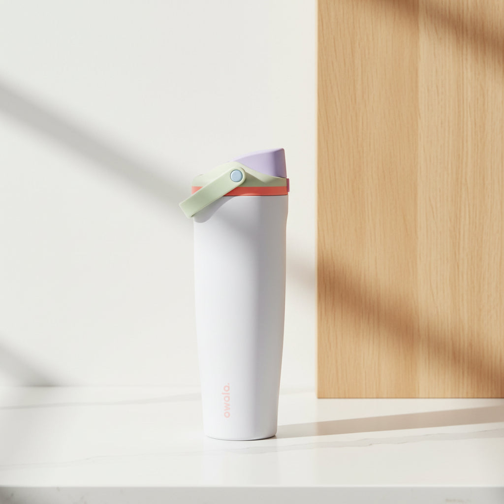 A white Owala travel tumbler with a coral-red flip-top lid and carrying loop, shown on a solid white background.