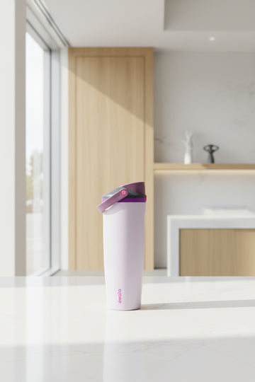 A light lavender Owala travel tumbler with a purple flip-top lid and a pink brand logo printed vertically near the bottom.