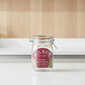 A Kilner round clip top jar made of clear glass with a dark red oval label and metal wire clamp lid, shown on a white background.