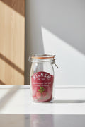 A Kilner round clip top jar made of clear glass with a dark red rubber seal and a metal wire clamp lid, featuring a printed red label with the Kilner brand name and a beet illustration.
