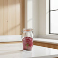 A Kilner round clip top jar made of clear glass with a dark red rubber seal and a metal wire clamp lid, featuring a printed red label with the Kilner brand name and a beet illustration.