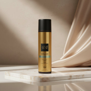 Ghd Bodyguard Heat Protect Spray in a 4 fl oz pump bottle. The bottle has a metallic gold body with a black cap and a black label featuring the 'ghd' logo.