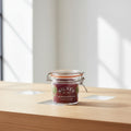 A Kilner round clip-top jar candle with a clear glass jar, metal wire bail, and orange rubber seal, filled with deep burgundy wax. The front label features the Kilner brand name and scent name 'Round Clip Top Jar'.
