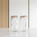 Two clear Kilner glass mason jars with wire bail lids and orange rubber gaskets, shown side by side on a white background.