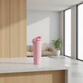 A pink Owala travel tumbler with a coral-red flip-top lid and carrying loop, shown on a solid white background.