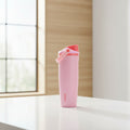 Pink water bottle with red cap on a white background