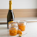 Bottle of champagne with two jars of orange marmalade on a wooden surface.