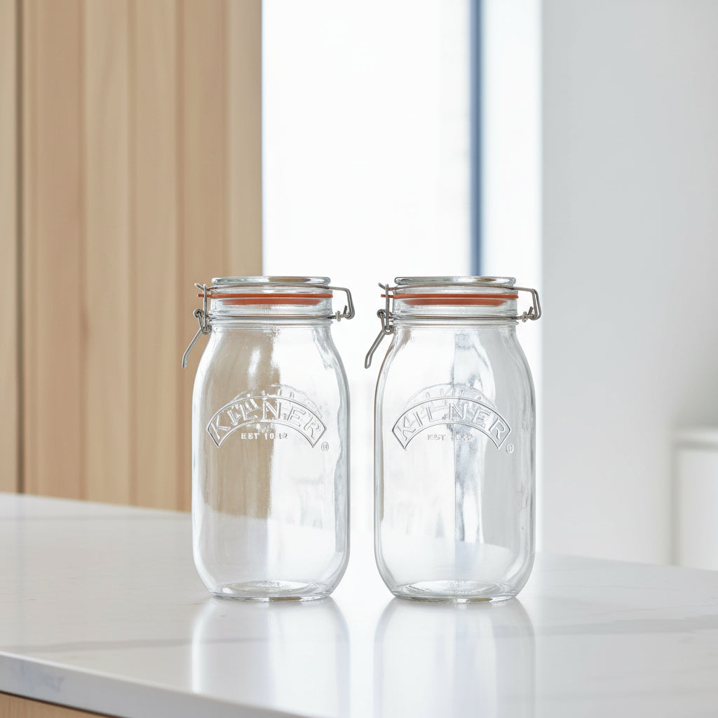 Two clear Kilner glass mason jars with wire bail lids and orange rubber gaskets, shown side by side on a white background.