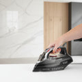 Person ironing clothes with a Russell Hobbs iron in a living room setting