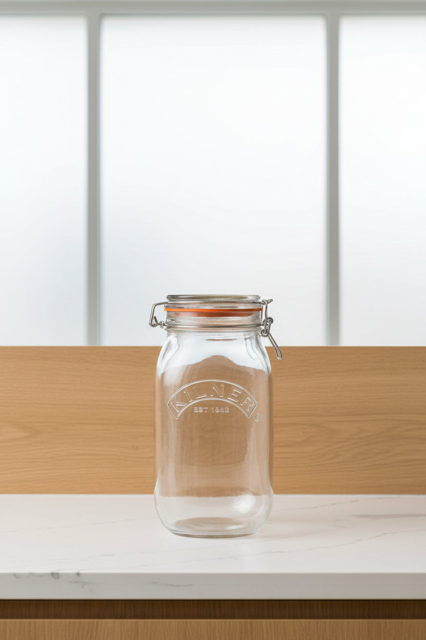 A Kilner glass jar with a metal clamp lid and orange rubber gasket, shown against a plain white background.