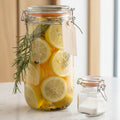 Glass jar with lemon slices and rosemary on a gray surface