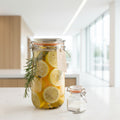 Glass jar with lemon slices and rosemary on a gray surface