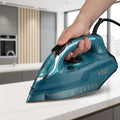 A teal and black Russell Hobbs PowerSteam Ultra steam iron being held by a hand against a white background.