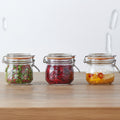 Three glass jars with metal clamps on a wooden surface, containing various contents.