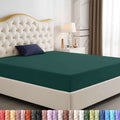 Navy blue fitted sheet on a bed with a decorative headboard and nightstand.