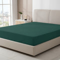 Navy blue fitted sheet on a bed with a decorative headboard and nightstand.