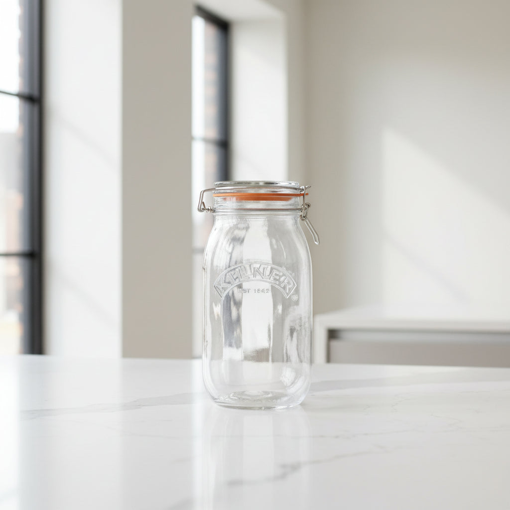 A clear glass jar with a metal clamp lid and orange seal, shown with dimension labels indicating 23 cm height and 11 cm width, alongside text stating 1.5 litre storage capacity and suitable contents biscuits, rice, and noodles.