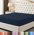 Navy blue fitted sheet on a bed with a decorative headboard and nightstand.