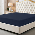 Navy blue fitted sheet on a bed with a decorative headboard and nightstand.