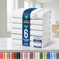 A stack of six folded fitted sheets wrapped in a blue paper band, shown on a white background with certification badges and a row of color swatches along the bottom.
