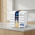 A stack of six folded fitted sheets wrapped in a blue paper band, shown on a white background with certification badges and a row of color swatches along the bottom.