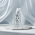 Clear spray bottle labeled 'WOW' with text highlighting product benefits on a blue background