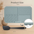 Gray silicone mat with textured surface and measurements, shown with a spatula for scale.