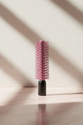 Pink round hairbrush on a black background