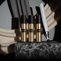 ghd hair care products including bottles and a flat iron on a dark surface with a gray background