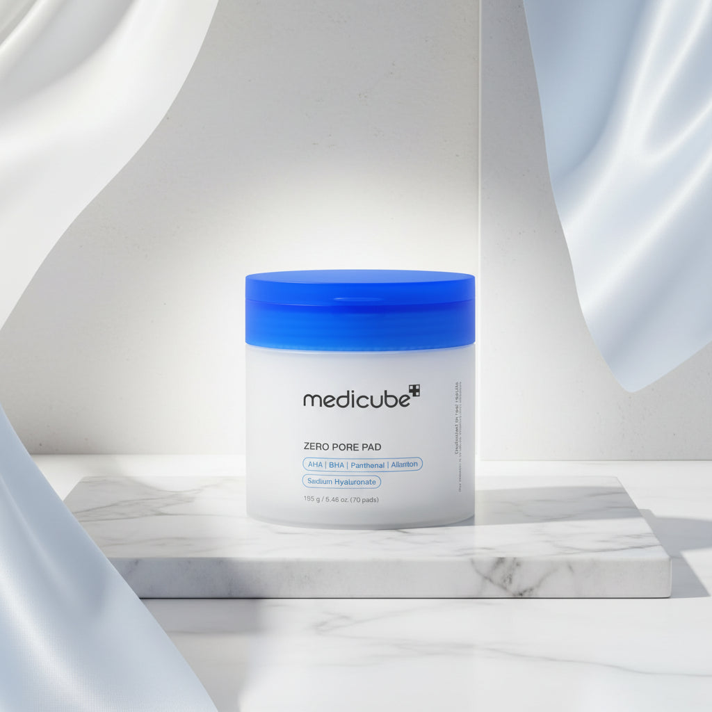 A white jar of medicube+ Zero Pore Pad with a bright blue lid, shown against a white circular background with a faint texture.