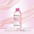 Garnier Micellar Cleansing Water All-in-1 for sensitive skin in a pink bottle with a pink flip-top cap, shown on a pale pink background. The left side includes Cruelty Free International and Vegan Formula badges.