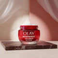 Olay Regenerist Ultra Rich Day Cream in a red jar with a white cream scoop on top, on a white background.