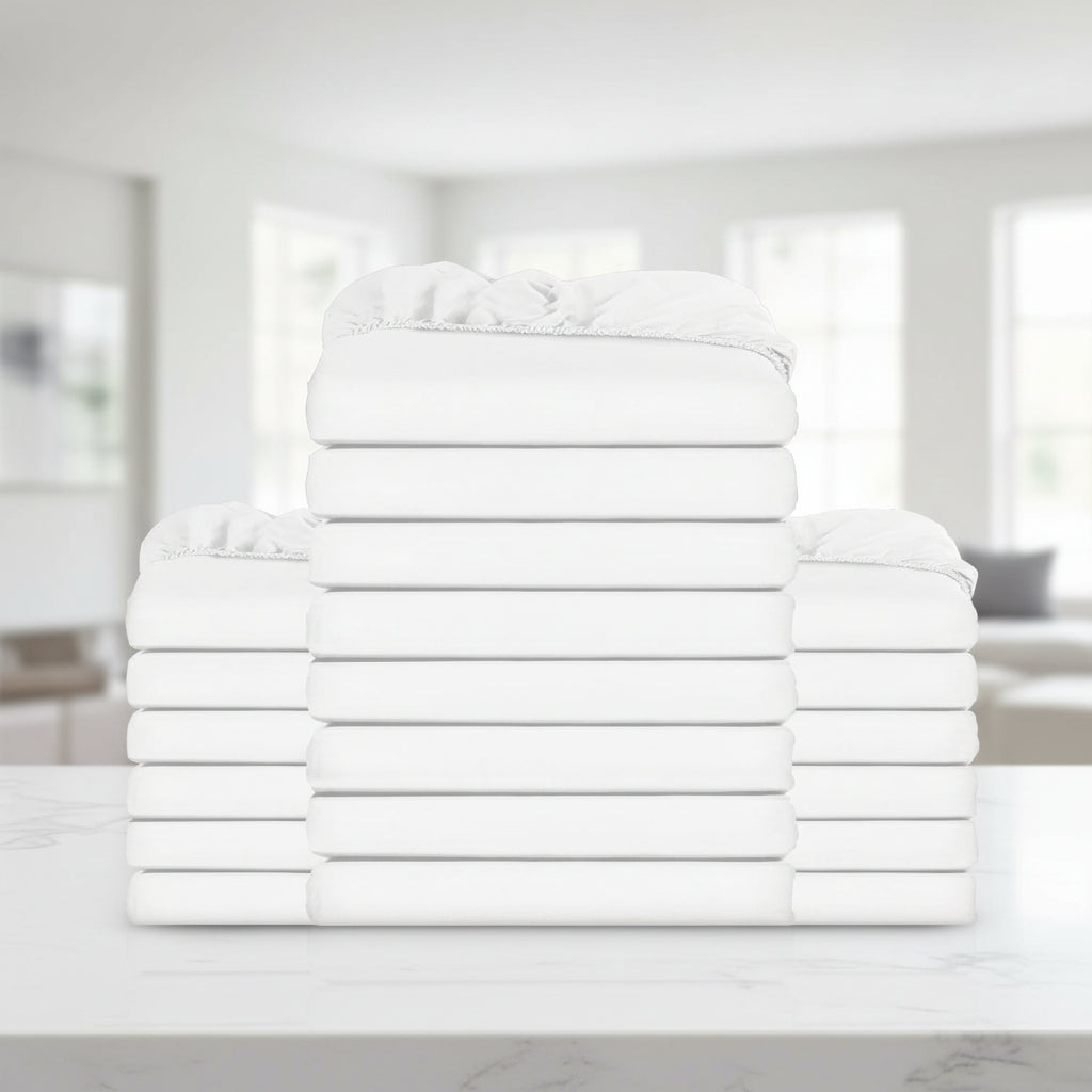 A stack of folded white bedding, including pillows and sheets, arranged symmetrically against a plain white background.