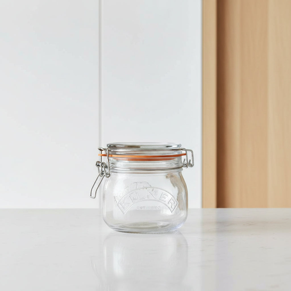 A Kilner glass jar with a metal clamp lid and orange rubber seal, shown on a plain white background.
