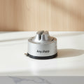 A close-up of a hand sharpening a stainless steel kitchen knife on a silver AnySharp electric knife sharpener, set against a clean white background.