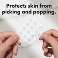 Hands holding a sheet of transparent stickers with small round dots against a light blue background.