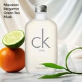 Calvin Klein CK One bottle with citrus fruits and green leaves on a white background