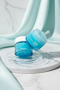 Neutrogena skincare jars with water droplets on a light blue background