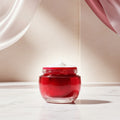 Olay Regenerist Day Cream in a red glass jar with a white cream swirl on top, on a white background.