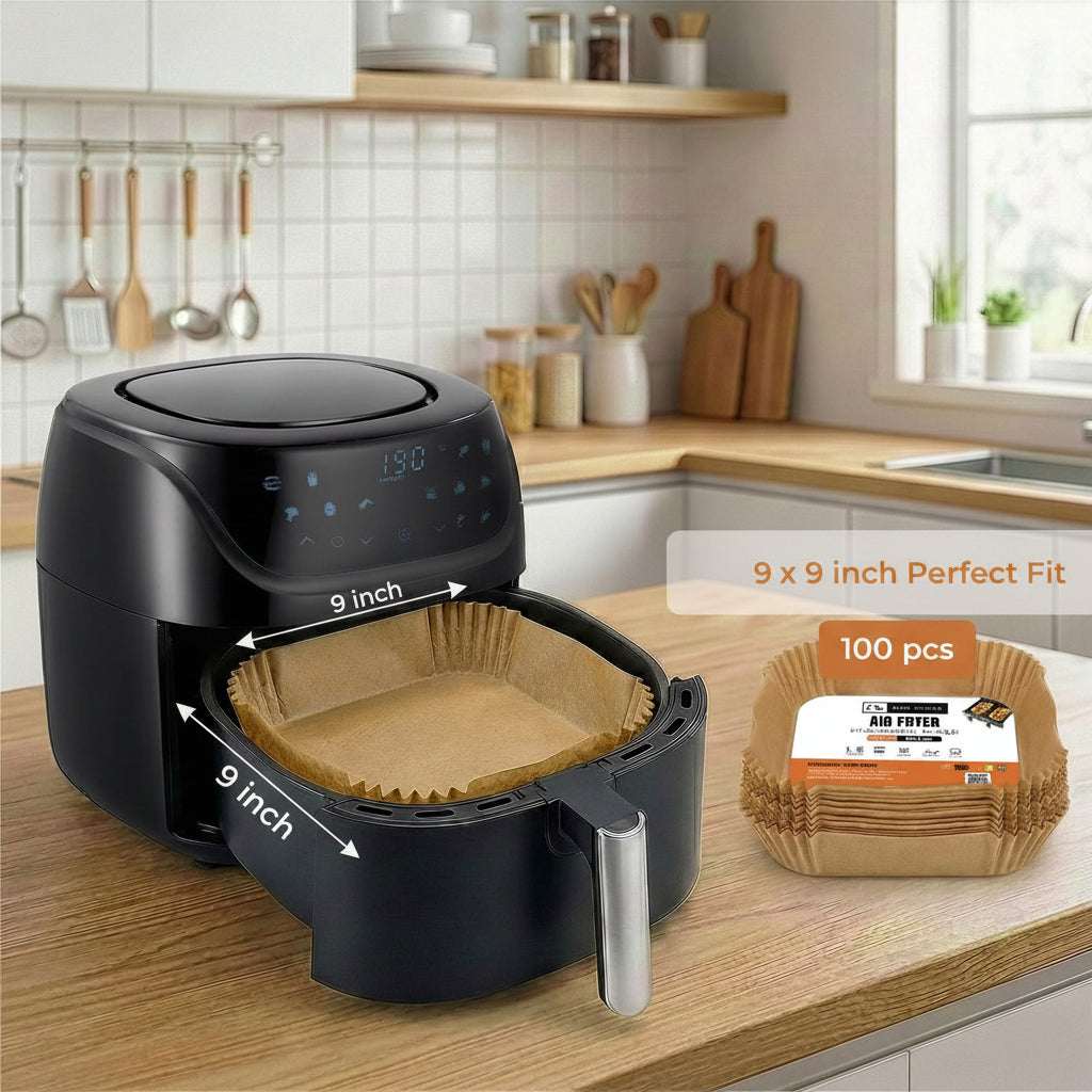 A black air fryer sits on a wooden kitchen counter with a paper liner inside, alongside a package of 100 brown 9-inch paper liners. A graphic overlay highlights the 9-inch fit, with a blurred kitchen background.