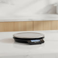 Digital kitchen scale with a clear platform on a white background