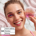 Woman using a makeup sponge applicator on her face with a pink background