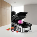 Multifunctional kitchen slicer with onion on top, surrounded by various attachments and vegetables.
