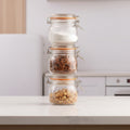 Three Kilner jars with metal clasps on a light surface with a blurred background