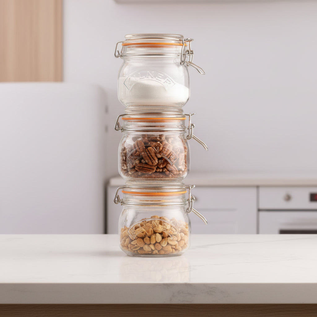 Three Kilner jars with metal clasps on a light surface with a blurred background