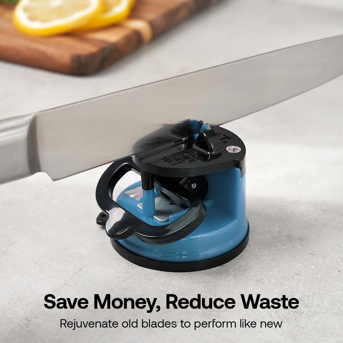 A kitchen knife being sharpened in a blue and black countertop knife sharpener, with a blurred cutting board and lemon slices in the background. Text at the bottom reads 'Save Money, Reduce Waste' and 'Rejuvenate old blades to perform like new.