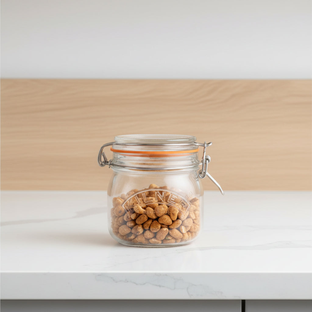 A clear glass clamp-lid jar with an orange seal, filled with almonds, on a light wooden surface against a soft lavender background.