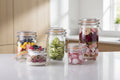 Collection of glass jars with various preserved foods on a dark surface