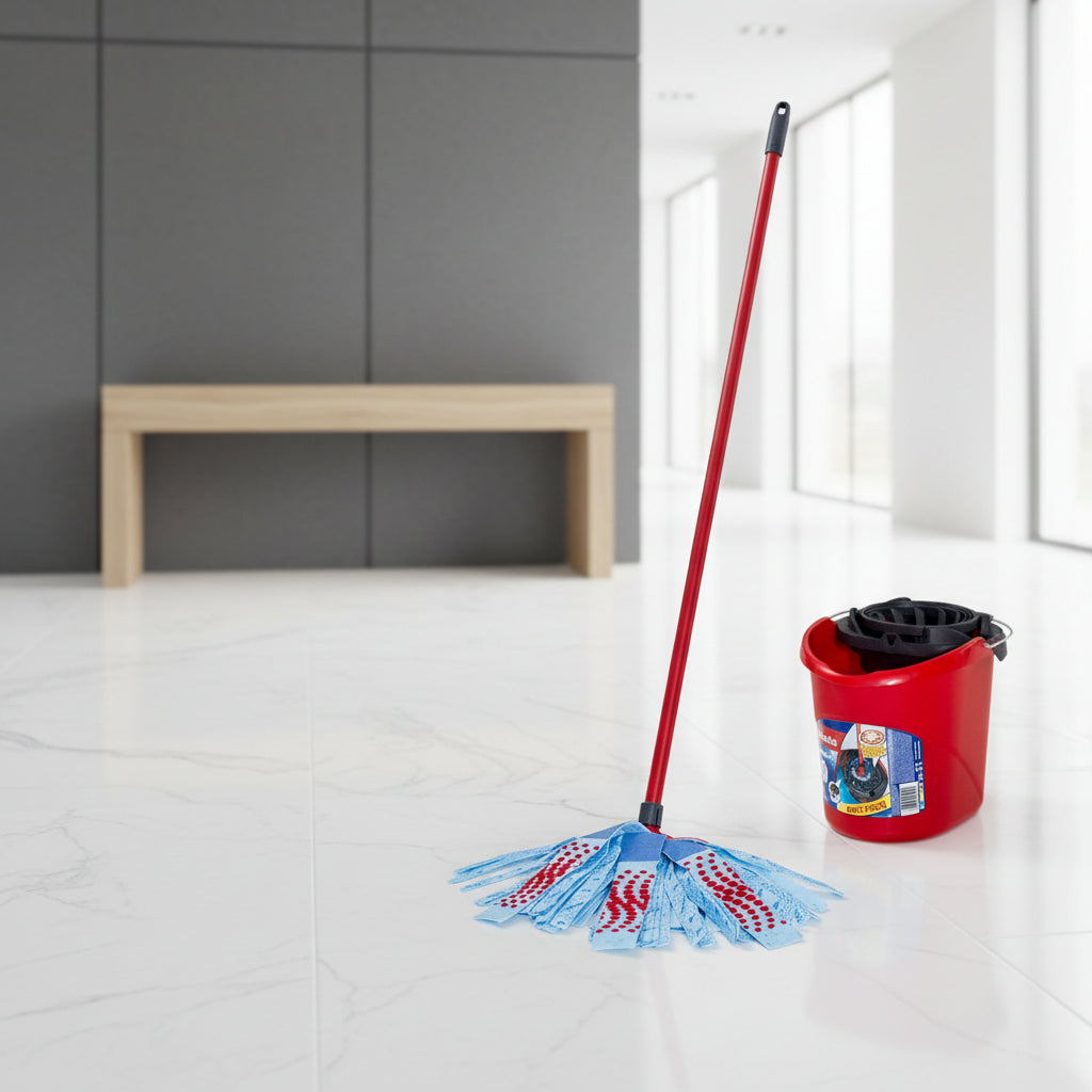 A person wearing blue jeans and tan wedge boots is mopping a white floor with a red-handled twist-mop style broom. A red bucket with a black wringer and a visible Clorox label sits nearby.