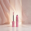 Maybelline New York Lash Sky Mega Glue in Pink Airide, showing the pink capless wand with a black handle and a matching pink product tube, set against a pink cosmetic swatch on a white background.